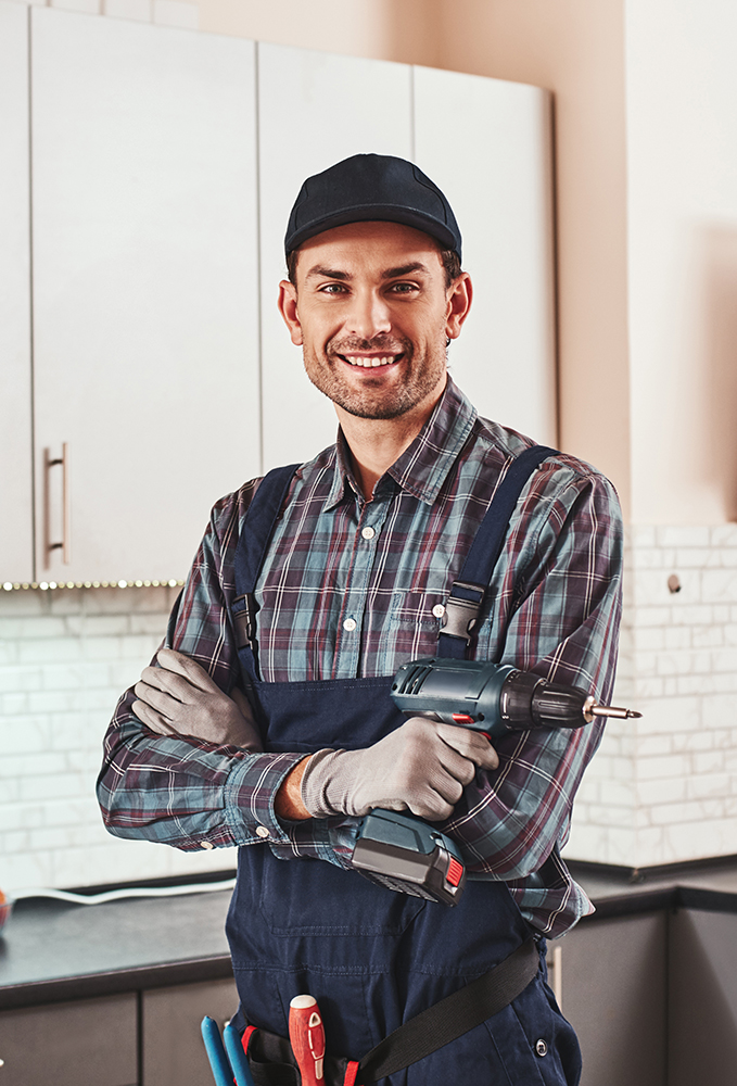Modern handyman. Portrait of a smiling male foreman standing with perforator